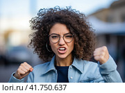 A young girl with curly hair rejoices in luck with her fists raised up. Generated by AI. Стоковое AI-изображение, AI-художник Ярославский Максим / Фотобанк Лори