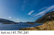 The beautiful blue lake of Patagonia. Small islands in the center. Yellowed grass on the shore. The Andes mountains on a background of azure sky and clouds. Lapataia Bay. Argentina. Ushuaia. Стоковое фото, фотограф Вера Ивановна Кубарева / Фотобанк Лори