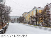 Вид на пустую заснеженную городскую улицу во время снегопада. На улице безлюдно. Холодная снежная погода. Магадан, Магаданская область, Дальний Восток России. Редакционное фото, фотограф Андрей Степанов / Фотобанк Лори