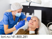 Cosmetologist making injections of botulotoxin in face of mature woman. Стоковое фото, фотограф Яков Филимонов / Фотобанк Лори