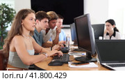 Concentrated young girl studying in computer lab with fellow students engrossed in coursework. Стоковое видео, видеограф Яков Филимонов / Фотобанк Лори