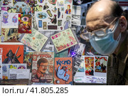 Посетитель ярмарки смотрит комиксы у стенда на международной ярмарке интеллектуальной литературы Non/fiction в Гостином дворе города Москвы, Россия (2023 год). Редакционное фото, фотограф Николай Винокуров / Фотобанк Лори
