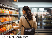 A woman who focuses on conscious consumption thoughtfully navigates the aisles of the supermarket, prioritizing nutritional value. Generated by AI. Стоковое AI-изображение, AI-художник Ярославский Максим / Фотобанк Лори