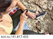 Latin woman, middle-aged, resting, regaining strength, eating, drinking water, after a gym session, burning calories, keeping fit, outdoors by the sea, wearing headphones and smart watch. Стоковое фото, фотограф carlos l vives / Фотобанк Лори
