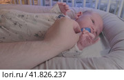 A newborn baby, one month old, cries in bed without a pacifier and calms down when his father helps him. Стоковое видео, видеограф Андрей Журавлев / Фотобанк Лори