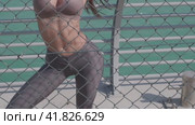 A young athletic woman with long hair, in leggings and a top stands at the pier against the backdrop of Dubai skyscrapers. Стоковое видео, видеограф Aleksey Kidisyuk / Фотобанк Лори