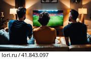 at home group of soccer fans on couch watch sport game on TV, online bet, celebrate when team wins championship. Friends cheer eat snacks, watch favorite football club play. AI. Стоковое AI-изображение, AI-художник Sergey Grishin / Фотобанк Лори