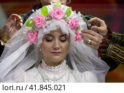 Женщины одевают фату и готовят невесту к свадьбе по традициям Донской казачьей свадьбы на выставке-форуме "Россия" на ВДНХ в городе Москве, Россия (2023 год). Редакционное фото, фотограф Николай Винокуров / Фотобанк Лори