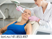 Young doctor doing RF lifting procedure for face lifting of adult woman laying in spa center. Smoothes wrinkles and tightens skin machine. Стоковое фото, фотограф Яков Филимонов / Фотобанк Лори