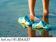 rubber slippers float in clear water next to female legs close up. Стоковое фото, фотограф Артем Курутин / Фотобанк Лори