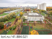 Москва, Россия, октябрь 2023 года. Вид на район Крылатское с высоты. Зеленый сквер, спортивная площадка, школа, жилые дома, гаражный комплекс, дорога, вид на Москву сквозь осеннюю дымку. (2022 год). Редакционное фото, фотограф Сергей Никифоров-Гордеев / Фотобанк Лори
