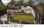 The ancient palace on the Royal Hill of Ambohimanga in Antananarivo. On the fenced territory, old wooden tombs with the remains of the rulers of Imerina are visible. Green grass on the lawn.Madagascar (2023 год). Стоковое фото, фотограф Вера Ивановна Кубарева / Фотобанк Лори