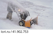 Male worker is using snowblower to remove snow after winter cyclone. Worker is blowing snow after blizzard (2023 год). Редакционное видео, видеограф А. А. Пирагис / Фотобанк Лори