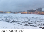 Winter view of the Neva River in the city center of St. Petersburg, Russia. Cracked ice floes on the surface of the water. Cold winter weather. Historical and modern buildings on the embankment. Стоковое фото, фотограф Андрей Степанов / Фотобанк Лори