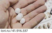 A man's hand pours white pills into the palm of his hand from a white jar. Background of blisters with medicines. Стоковое видео, видеограф Ярославский Максим / Фотобанк Лори