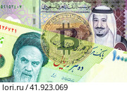 Saudi Arabia Riyal banknote with King Salman, Iranian rial banknote with Ayatollah Khomeini and translucent Bitcoin. Стоковое фото, фотограф FotograFF / Фотобанк Лори