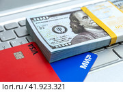 Карты VISA и МИР с пачкой долларов на клавиатуре ноутбука. Краеугольный камень экономики. (2024 год). Редакционное фото, фотограф Ярославский Максим / Фотобанк Лори