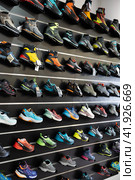 On black wooden wall of showcase - there are samples of models of hiking and climbing shoes (2023 год). Редакционное фото, фотограф Яков Филимонов / Фотобанк Лори