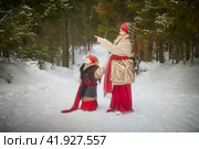 Teen and little girl in thick coat in cold winter day in forest. Medieval peasant sisters collecting firewood. Photoshoot in stile of Christmas fairy tale. Стоковое фото, фотограф Кривошеина Елена Леонидовна / Фотобанк Лори