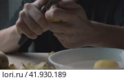 Men's hands peel potatoes at the kitchen table. A cinematic picture. The passage is from right to left. Стоковое видео, видеограф Ярославский Максим / Фотобанк Лори