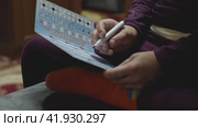 A child is playing a board game where you have to draw on a tablet. He is sitting on the couch. The concept of developmental games. Krasnodar, Russia, September 25, 2021. Редакционное видео, видеограф Воловодов Владимир / Фотобанк Лори