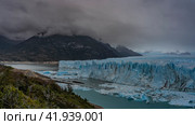 The breathtaking landscape of the Perito Moreno Glacier. An array of blue ice stretches to the horizon between the mountains. A glacial wall with cracks and sharp peaks rises above the lake. Fog. Стоковое фото, фотограф Вера Ивановна Кубарева / Фотобанк Лори
