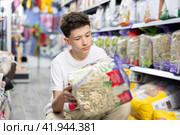 Teen boy take hay from shelf in pet store. Стоковое фото, фотограф Яков Филимонов / Фотобанк Лори