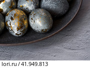Stylish grey Easter eggs made of marble and concrete with a golden potala on a grey background. Coloring eggs with natural dye karkade tea. Environmental friendliness. Naturalness. The concept of a happy Easter. (2023 год). Стоковое фото, фотограф Photojuli / Фотобанк Лори