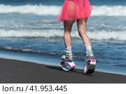 Rear view woman running and jumping on beach during aerobic workout. Female in Kangoo Jumps boots and short pink skirt. Low section, crop view (2022 год). Редакционное фото, фотограф А. А. Пирагис / Фотобанк Лори