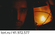 A man's face in the dark close-up illuminated by a kerosene lamp. Halloween Concept. Стоковое видео, видеограф Воловодов Владимир / Фотобанк Лори
