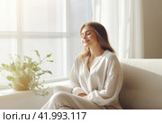A seated young woman relaxes on the sofa. Стоковое AI-изображение, AI-художник Татьяна  Бральнина / Фотобанк Лори
