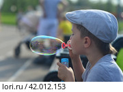 Мальчик надувает мыльные пузыри в парке. Стоковое фото, фотограф Оксана / Фотобанк Лори