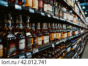 Whiskey bottles on the shelves of a liquor Store. Advertising banner. Стоковое AI-изображение, AI-художник Ирина Ручушкина / Фотобанк Лори