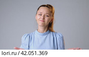 Doubtful young woman refusing gesture hesitating on gray background in studio. Стоковое видео, видеограф Сергей Толмачёв / Фотобанк Лори