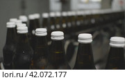 Крупный план белых крышек на стеклянных бутылках, движущихся по конвейеру. Производство питьевой воды на заводе пищевой промышленности. Стоковое видео, видеограф Воловодов Владимир / Фотобанк Лори