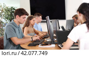 Focused young guy studying in computer lab with fellow students engrossed in coursework. Стоковое видео, видеограф Яков Филимонов / Фотобанк Лори