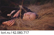 A young beautiful girl lies in a field on dry grass and looks at the camera. Стоковое видео, видеограф Strunov David / Фотобанк Лори
