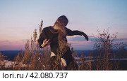 A young girl dancing in the grass against the background of the setting sun. Стоковое видео, видеограф Strunov David / Фотобанк Лори