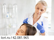 Elderly woman trichologist doing injections into female patient scalp. Стоковое фото, фотограф Яков Филимонов / Фотобанк Лори