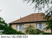 Modern house with chimney, red clay tiled roof and gable and valley type of roof construction. Roofing Construction. Стоковое фото, фотограф Сахарова Мария Юрьевна / Фотобанк Лори