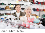 Elderly mom strongly recommends her doughter to pay attention to classic model of light sneakers. Стоковое фото, фотограф Яков Филимонов / Фотобанк Лори