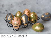 Stylish beautiful Easter eggs with golden potali coating on a gray background. The concept of happy Easter 2024. Стоковое фото, фотограф Photojuli / Фотобанк Лори