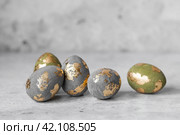Stylish beautiful Easter eggs with golden potali coating on a gray background. The concept of happy Easter 2024. Стоковое фото, фотограф Photojuli / Фотобанк Лори