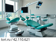 Interior of dental equipment in dentist office in new modern stomatological clinic room. Background of dental chair and accessories used by dentists in blue color. Copy space, text place. Стоковое AI-изображение, AI-художник Aleksandr Golubev / Фотобанк Лори