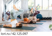 Young women practicing Salamba Sarvangasana Baddha Konasana in yoga studio. Стоковое фото, фотограф Яков Филимонов / Фотобанк Лори
