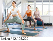 Smiling girl performing Utkata Konasana at group yoga training. Стоковое фото, фотограф Яков Филимонов / Фотобанк Лори