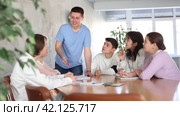 Young lecturer and group of interested grown-up students discussing notes around large desk. Стоковое видео, видеограф Яков Филимонов / Фотобанк Лори