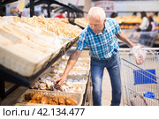 Old age senor examines bakery products in the grocery section of the supermarket. Стоковое фото, фотограф Татьяна Яцевич / Фотобанк Лори