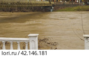 Flooding a brown muddy river. A fast flowing stream after heavy rain. A dangerous river threatening to rise to level of a footbridge. Environmental disaster. A global warming problem. Weather disaster. Стоковое видео, видеограф Воловодов Владимир / Фотобанк Лори