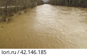 View from bridge on muddy river during flooding. Natural disasters, extreme weather. A weather disaster. Stormy brown river carrying debris. River spill, Environmental disaster, Global warming problem. Стоковое видео, видеограф Воловодов Владимир / Фотобанк Лори